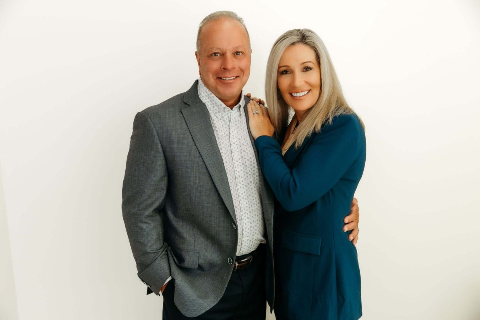 A smiling couple posing together against a white background.