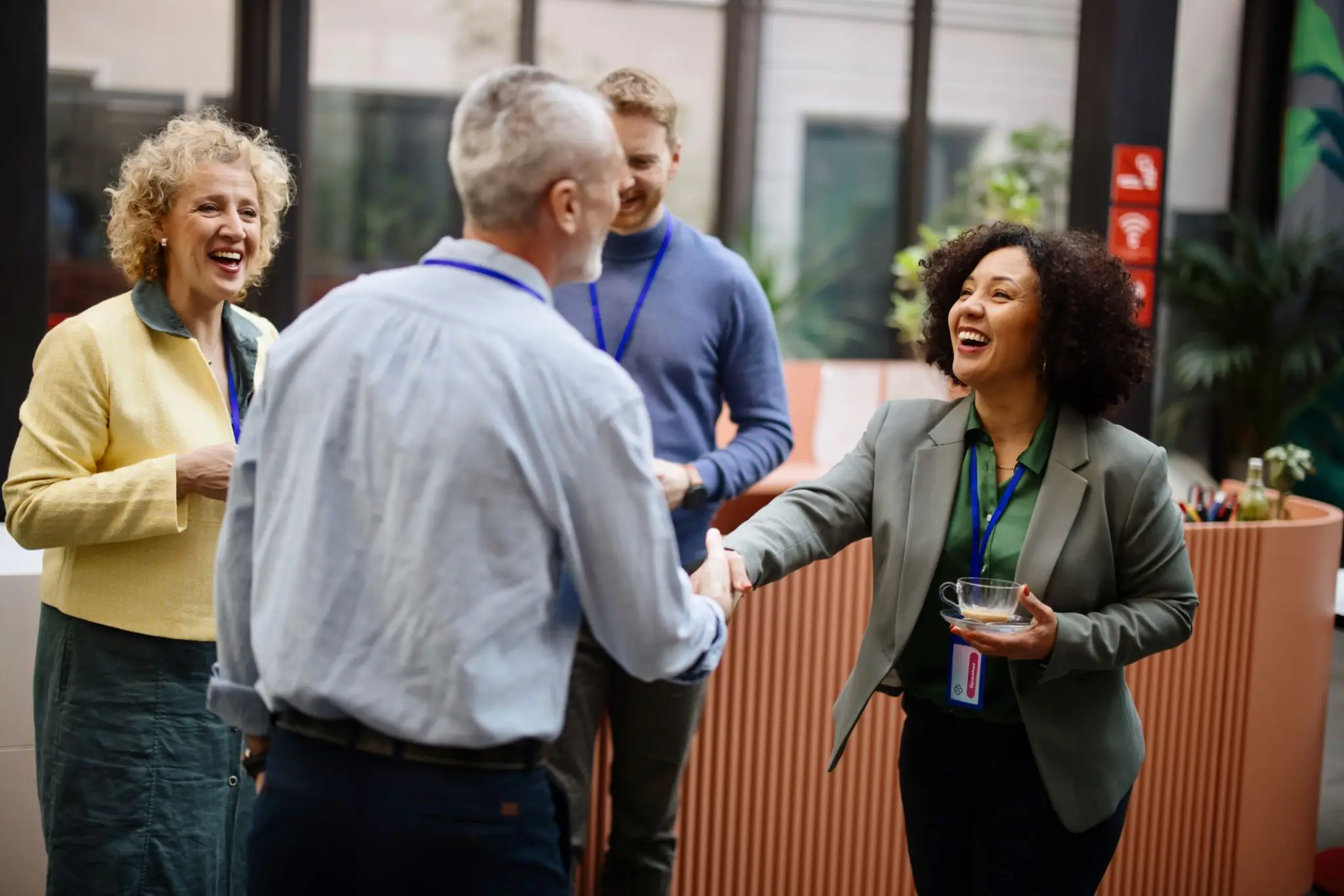 Two colleagues shaking hands in a friendly office setting.