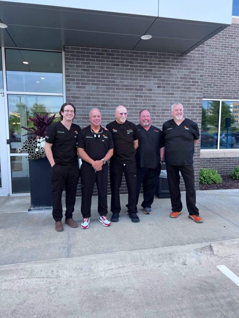 Five people in matching black outfits standing outside a building.
