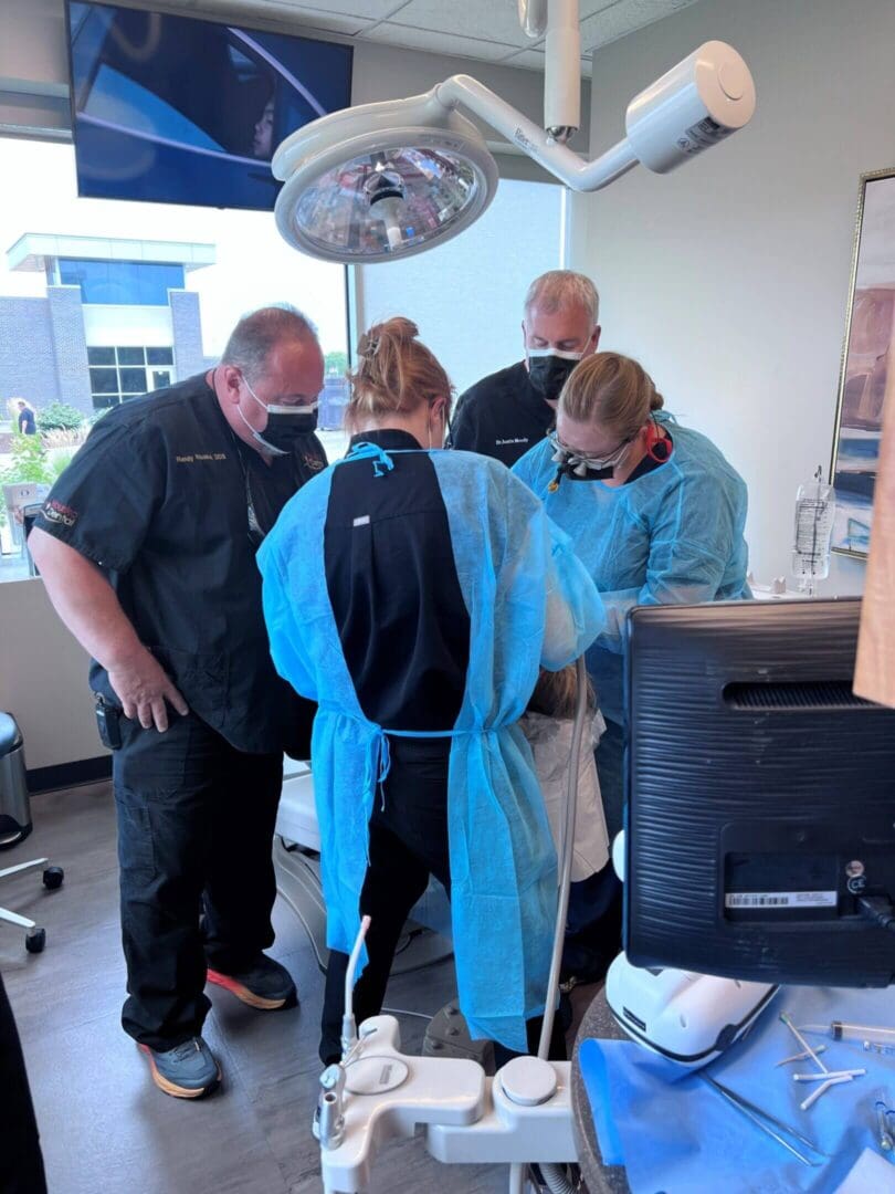 Healthcare professionals in PPE attending to a patient in a clinical setting.