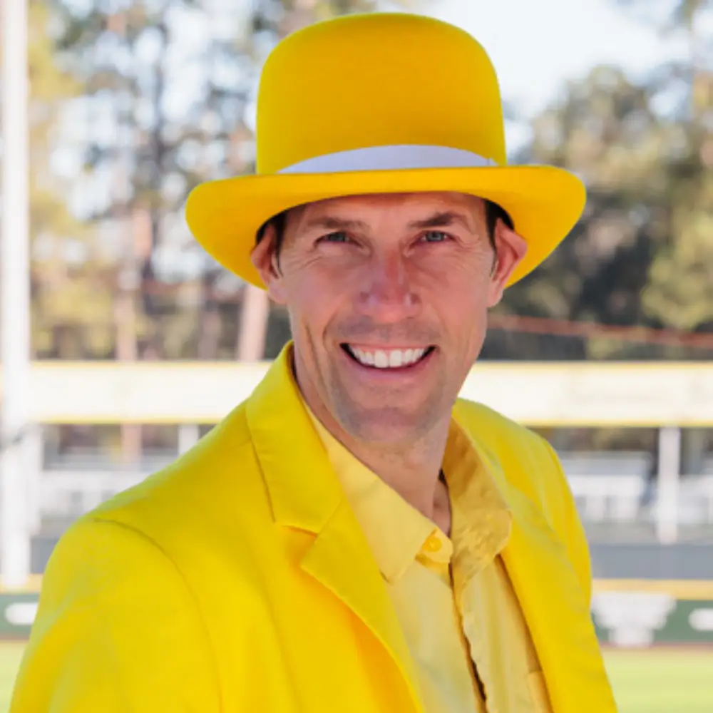 Man wearing a bright yellow hat and matching jacket, smiling outdoors.